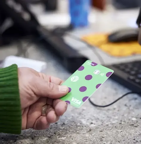 Image of a person's hand holding an Everwise card getting ready to hand it over the counter to a branch teller