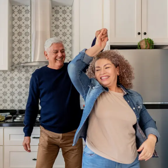 Senior couple dancing on kitchen at home - stock photo