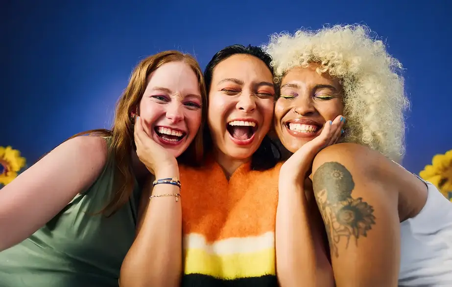 Three women with big, laughing smiles posing together
