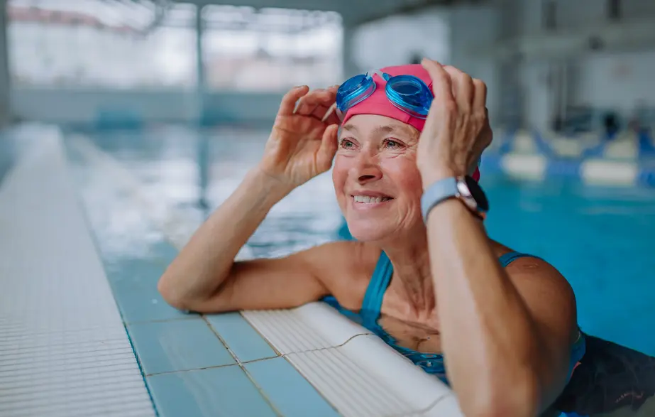 Woman swimming in a pool with goggles and a smart watch.