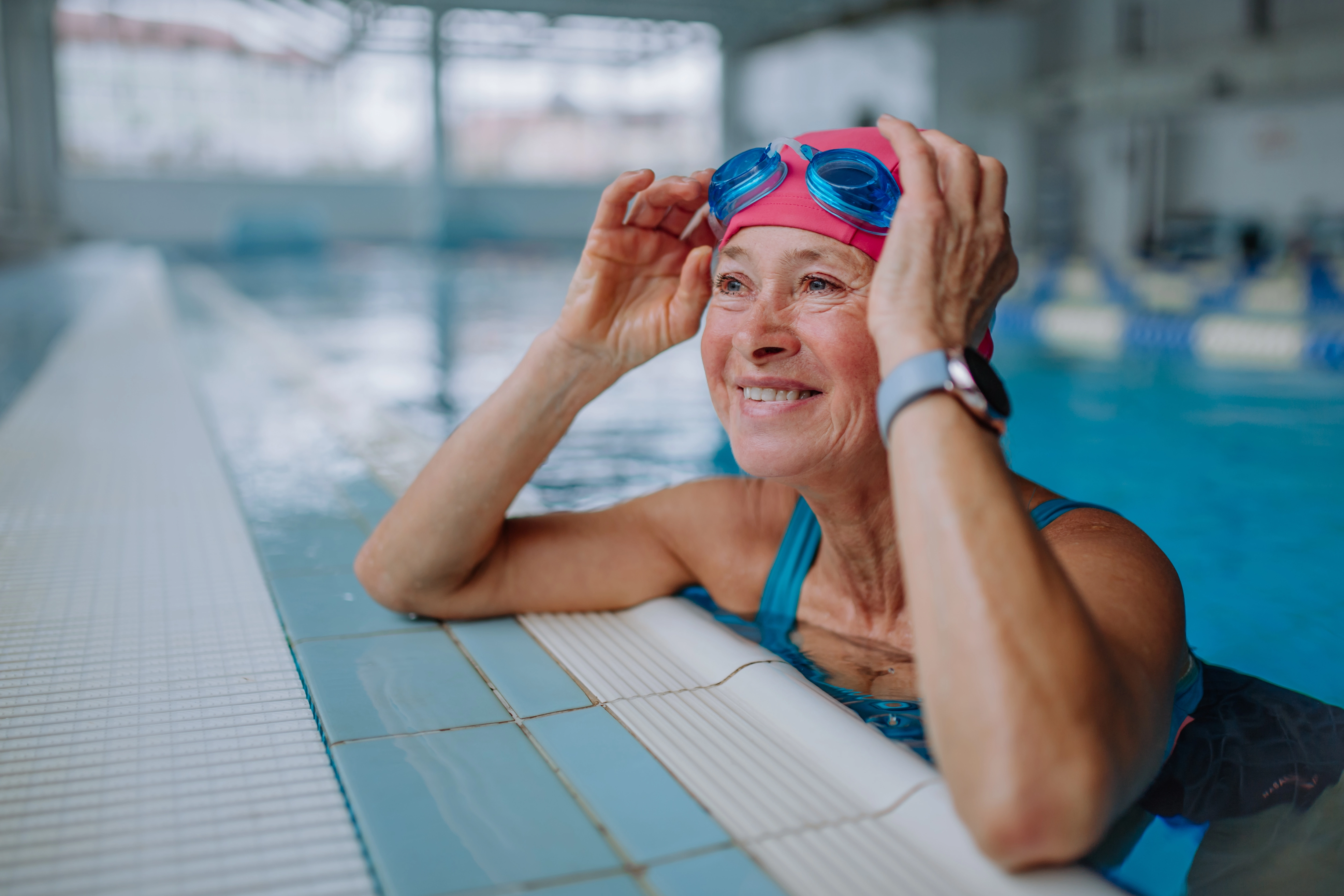 Woman swimming in a pool with goggles and a smart watch.