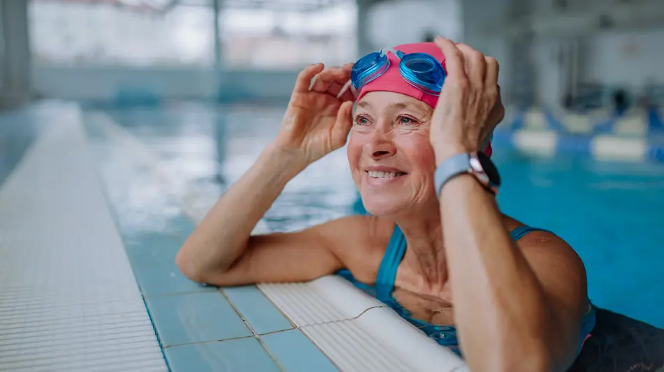 Woman swimming in a pool with goggles and a smart watch.