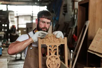 A carpenter sanding a chair he's building. 