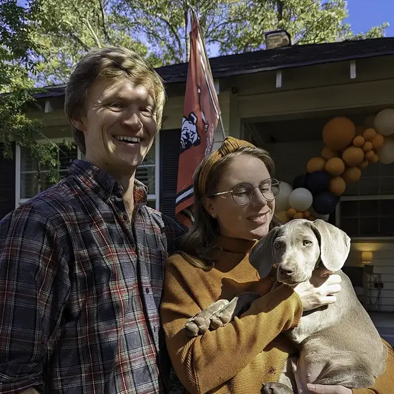 couple outside of home with pet dog