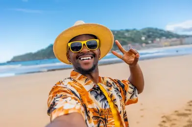 man enjoying sun on beach with peace sign image