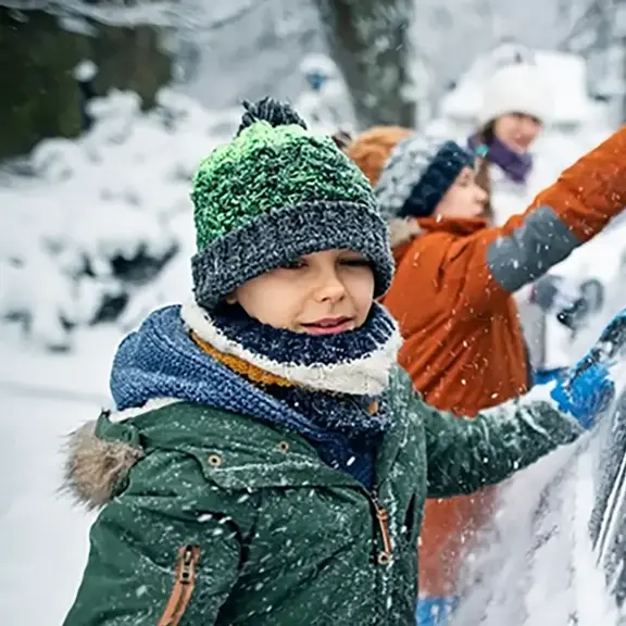 Children are scraping snow off a car window