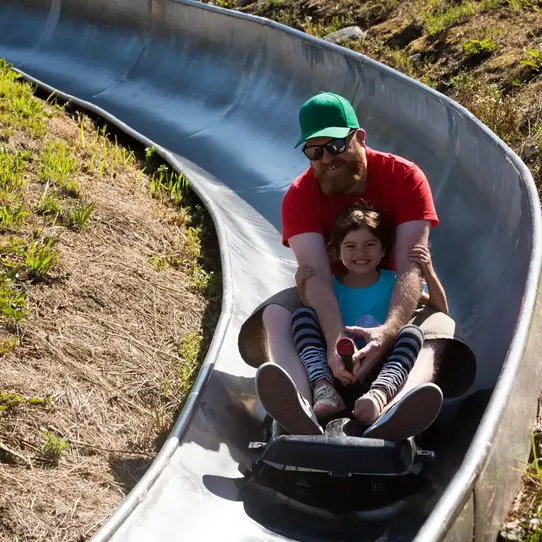 Father daughter enjoying toboggan run in summer