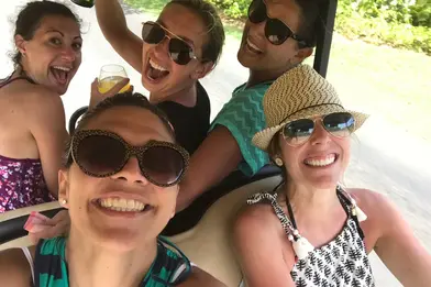 A group of women driving around and having fun in a golf cart. 