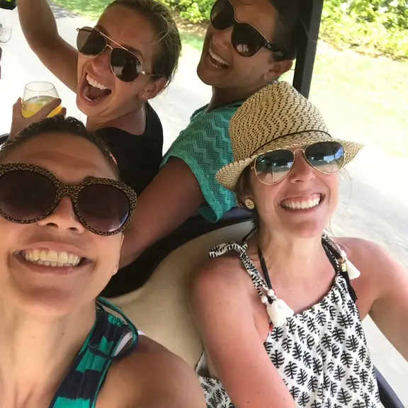 A group of women driving around and having fun in a golf cart. 