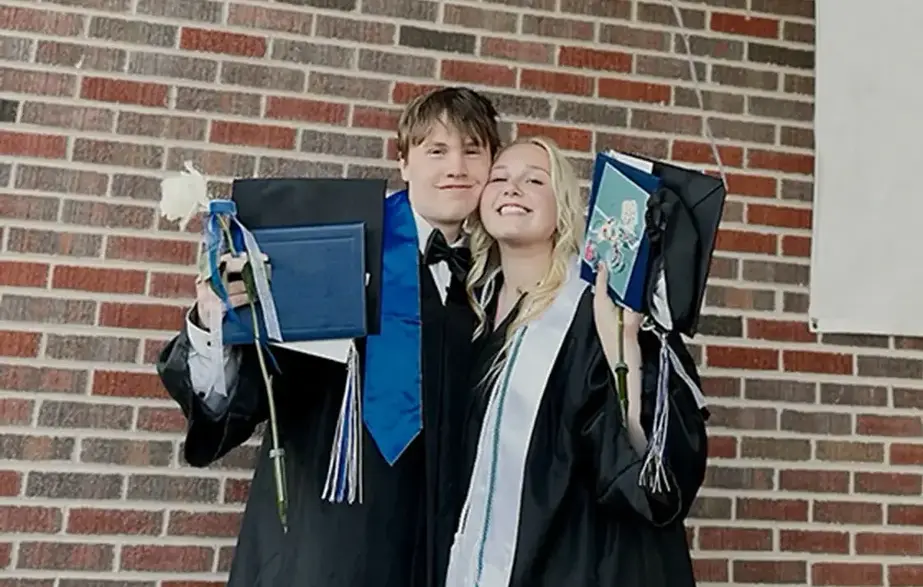 two high school graduates posing