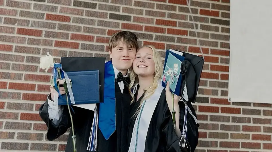 two high school graduates posing