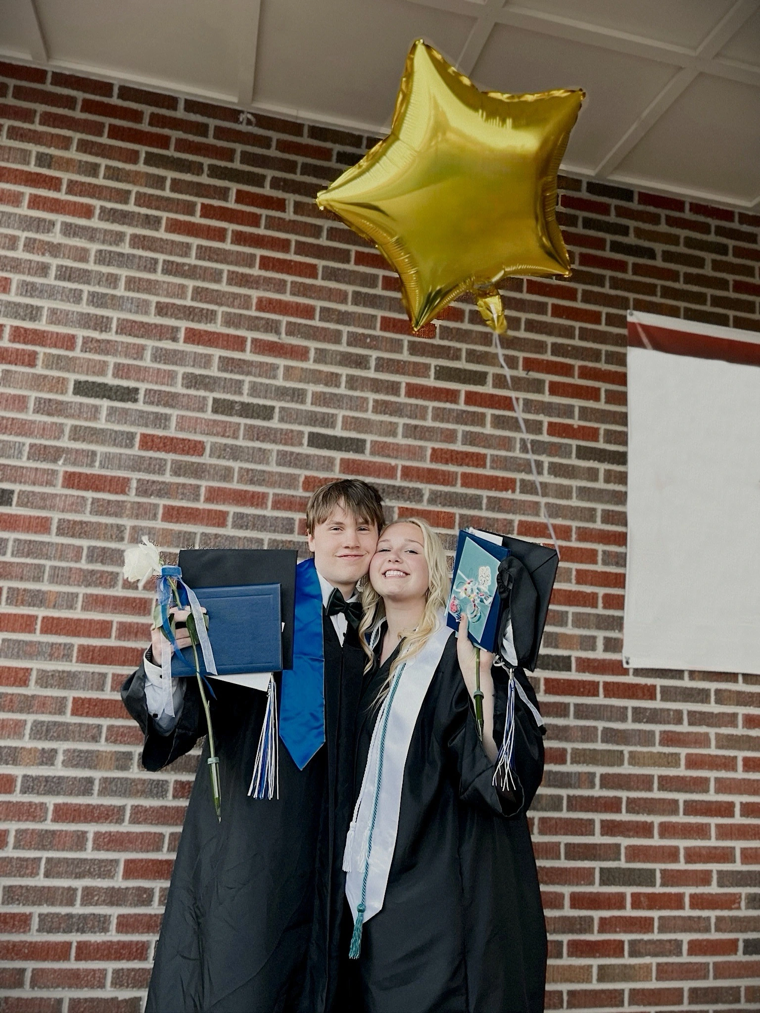 two high school graduates posing